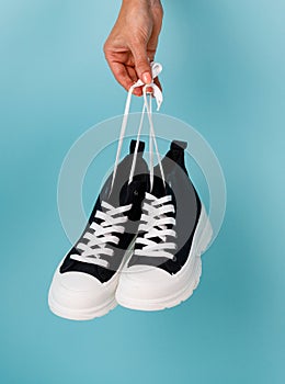 Stylish and fashionable model of black and white sneakers on blue background.