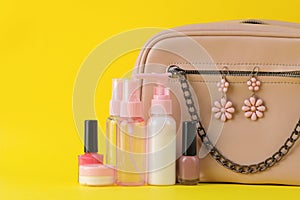 Stylish fashionable pink bag and women`s cosmetics and accessories on a bright trendy yellow background. female accessory concept