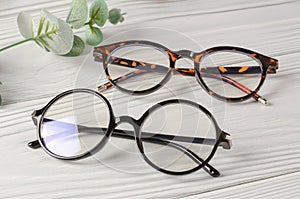 Stylish female glasses on white wooden table