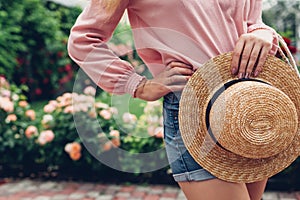 Stylish female handbag and straw hat. Young woman holding beautiful summer accessories outdoors. City fashion
