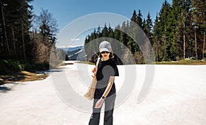 Stylish female hiker walking in a mountain resort, standing in the snow while walking in the mountains