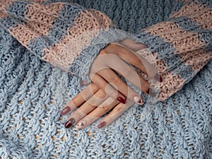 Stylish female manicure. Young female hands in woolen material