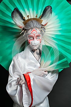 Stylish female model woman with makeup wearing mask and stage costume. Halloween, carnival, performance and theater concept