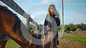 Stylish female posing near grazing horse