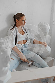 Stylish female sculptor in casual attire, sitting comfortably