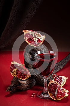Stylish food photography in the theater surroundings - ripe pomegranate and pomegranate juice. Shooting in a discreet style