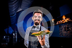 Stylish garcon serves dish on a black background.