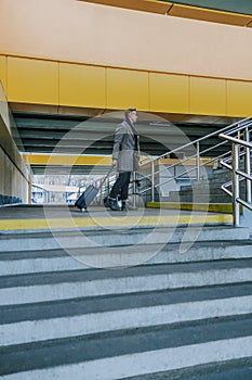 Stylish gentleman with trolley bag standing at railway station