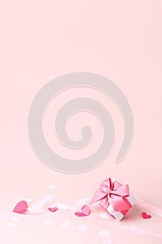 Stylish gift box with big pink bow and tender paper craft pink hearts on pink background, copy space, Greeting card, banner, flyer