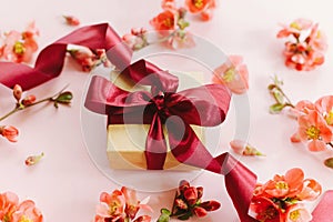 Stylish gift box with flowers on pink background composition. Happy Mothers day. Greeting card template. Craft gift with ribbon