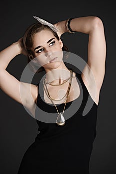 Stylish girl in a black dress and gold jewelry