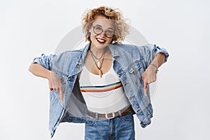 Stylish girl with blond short haircut in glasses and trendy top with rainbow smiling broadly gazing at camera assuring