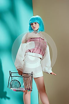stylish girl in blue wig holding transparent cosmetic bag