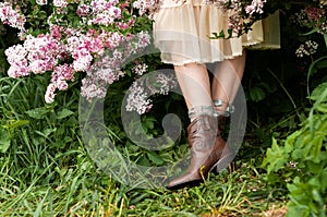 Stylish girl in brown cowboy boots under a skirt