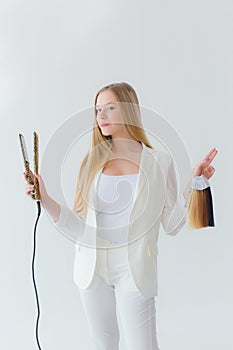 Stylish girl with curling iron on white background
