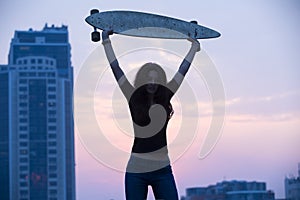 Stylish girl in jeans holding aloft longboard