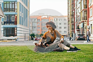 Stylish girl playing with a beautiful brown puppy on the lawn, smiling and stroking the dog. Beautiful lady is having fun on the