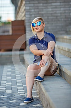 Stylish girl in sunglasses listens to headphones