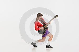 Stylish girl, retro musician wearing vintage style bright clothes playing guitar like rockstar  on white