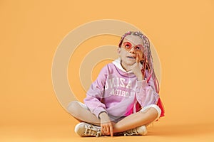Stylish girl in rounded glasses with pink dreadlocks sitting, th