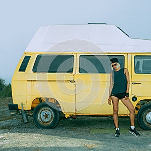 Stylish girl stands near vintage minibus. Urban fashion style