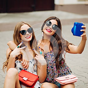 Stylish girlfriends tacking self portrait on polaroid.