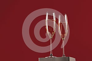 Stylish glasses of champagne on a stand on a red background
