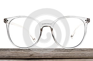 Stylish glasses with transparent frame on wooden table against white background