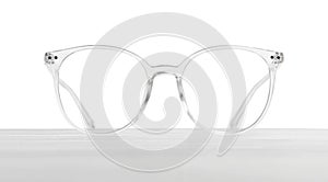 Stylish glasses with transparent frame on wooden table against white background