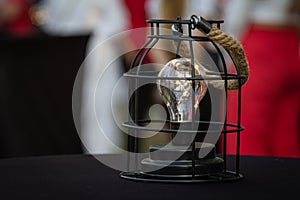 Stylish glowing lamp with light bulb on black table in the garden