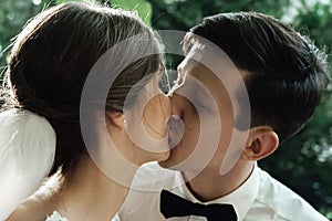 Stylish gorgeous happy bride and groom kissing at wedding reception, emotional cheerful moment