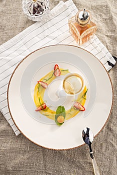 Stylish gourmet dessert with vanilla ice cream and fruit served on white plate at restaurant