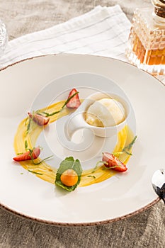 Stylish gourmet dessert with vanilla ice cream and fruit served on white plate at restaurant