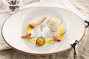 Stylish gourmet dessert with vanilla ice cream and fruit served on white plate at restaurant