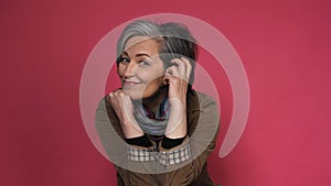 Stylish graying Woman charmingly smiles looking at camera. Caucasian mid aged dressed in brown corduroy jacket with