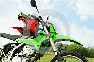 Stylish green cross motorcycle with helmet outdoors