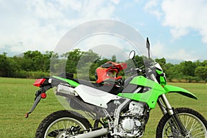 Stylish green cross motorcycle with helmet outdoors