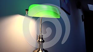 A stylish green reading lamp stands on a brown desk. Luxurious apartment decor.