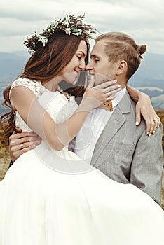 Stylish groom carrying happy bride and hugging, romantic tender