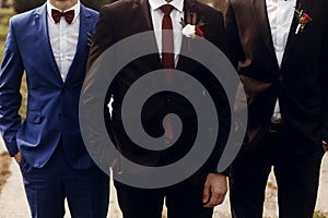 Stylish groom with groomsmen in suits with boutonniere posing, g photo