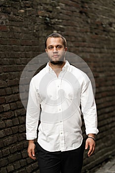 Stylish groom in a white shirt. Wedding portrait. Young guy in white shirt and black trousers. Handsome smart man in