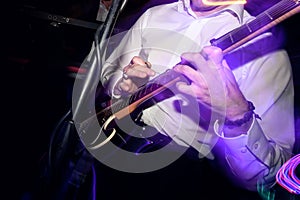 stylish guitarist playing on a stage with a band on wedding reception with cool motion light
