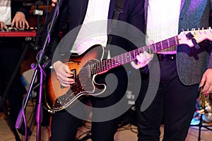 stylish guitarist singer playing on a stage with a band on wedding reception