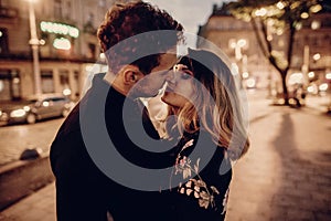 Stylish gypsy couple in love hugging and kissing in evening city