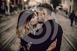 stylish gypsy couple in love kissing hugging in evening city street. woman and man gently embracing, romantic french atmospheric