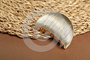 Stylish hair clip and wicker mat on background