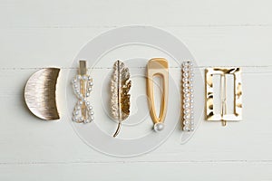 Stylish hair clips on wooden table, flat lay