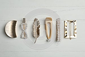 Stylish hair clips on white wooden table, flat lay