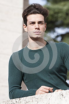 Stylish hair young man outdoors on the ledge, tight knit