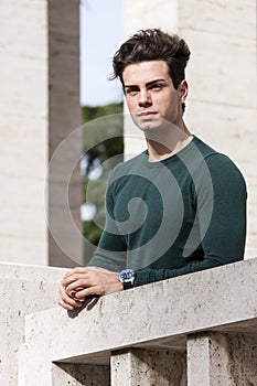 Stylish hair young man outdoors on the ledge, tight knit